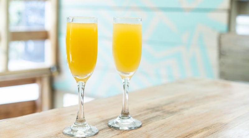 Deux verres de jus d'orang posés sur une table.