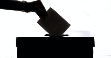 Une personne glissant son bulletin de vote dans une urne.