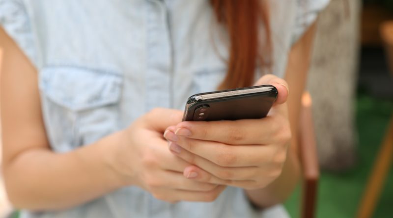 Une jeune femme manipulant son smartphone (Photo : Unsplash).